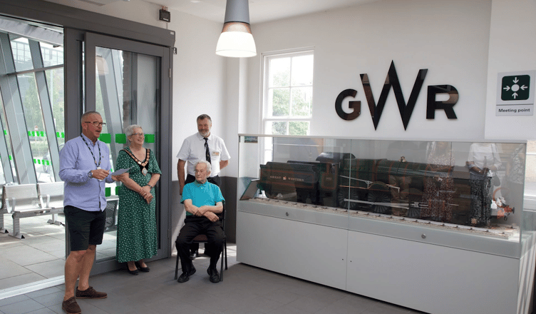 West Somerset Railway Association volunteer Clive Goddard (seated) is pictured with a model locomotive he made from recycled metals and which now has pride of place at Taunton Station, where he began his career in 1949.