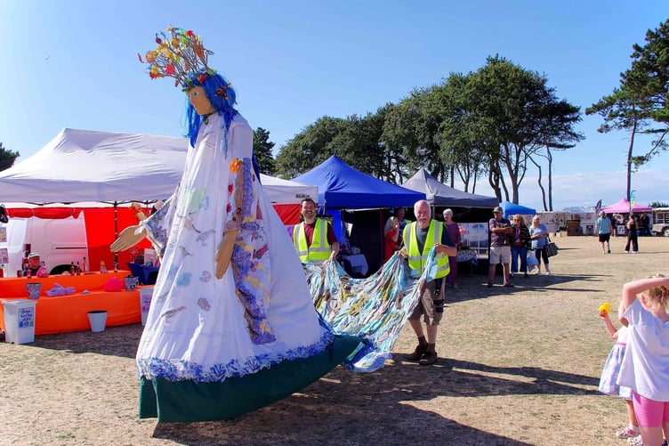 A stilt walker at Watchet Carnival is given a helping hand.