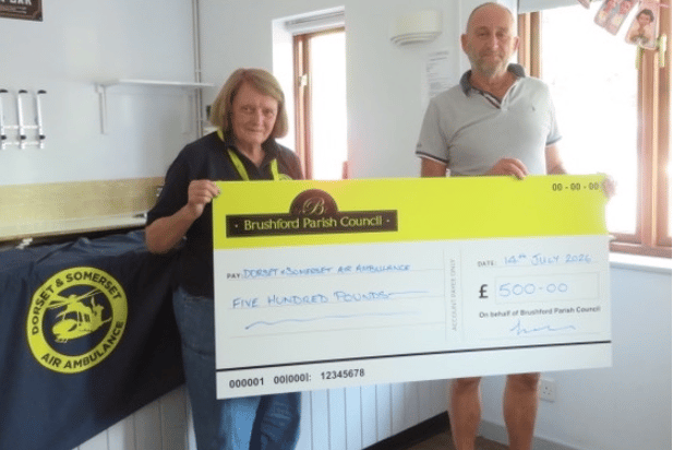Brushford Parish Council chairman Cllr Nick Prouse hands a cheque to Dorset and Somerset Air Ambulance fund-raiser Barbara Wilson.