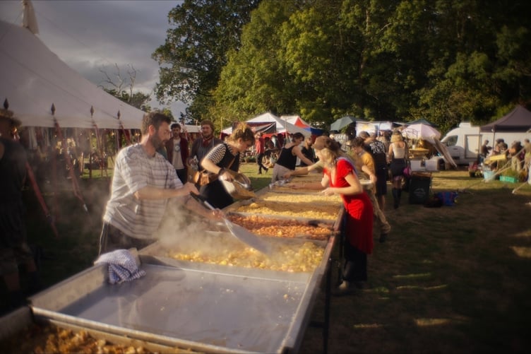 Volunteers help prepare Ferally Good Folk Festival's giant apple crumble, using apples and baking trays from West Somerset.